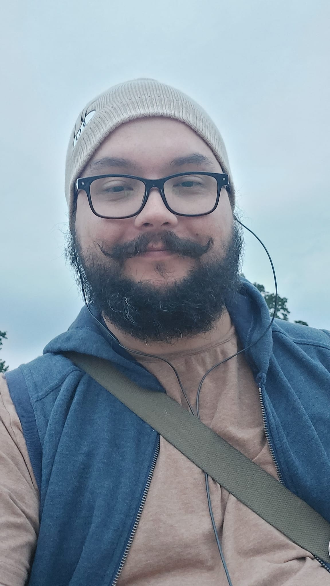 A man with short hair and bushy facial hair sits at the Balm Beach waterfront